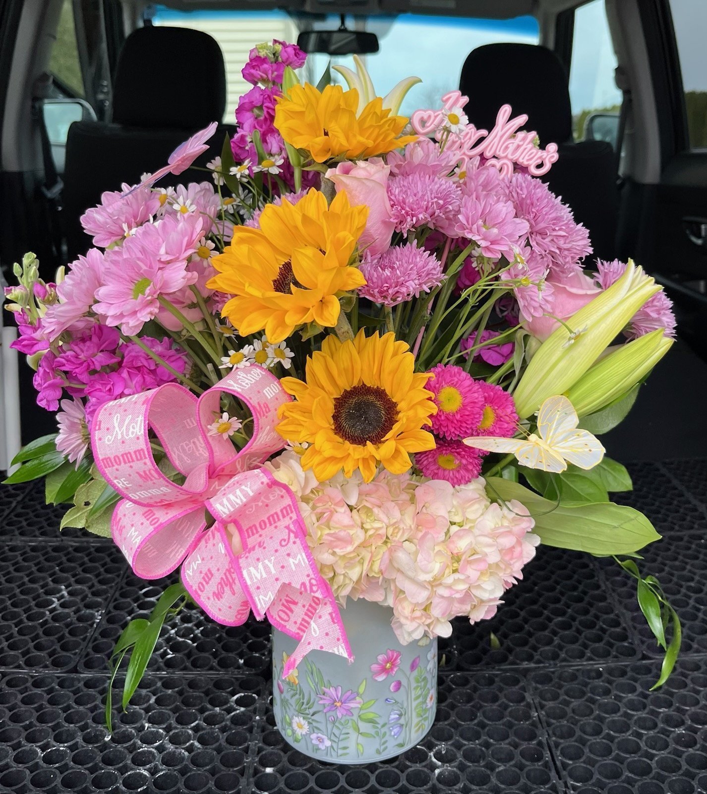 Country Charm Floral and Gifts | Florist LaPorte Indiana Mothers Day Surprise - A Vibrant, Fragrant Floral Arrangement perfect for Mother's Day & Springtime Joy. Nestled within this large, cheerful arrangement—you’ll find an abundant mix of fresh, vibrant flowers decorated with artificial butterflies. The beautiful and feminine floral vase ties everything together, especially for Mother's Day! This makes the perfect gift for any mom or mommy-to-be! Local Flower Delivery throughout LaPorte County, Indiana 7 Days a Week.